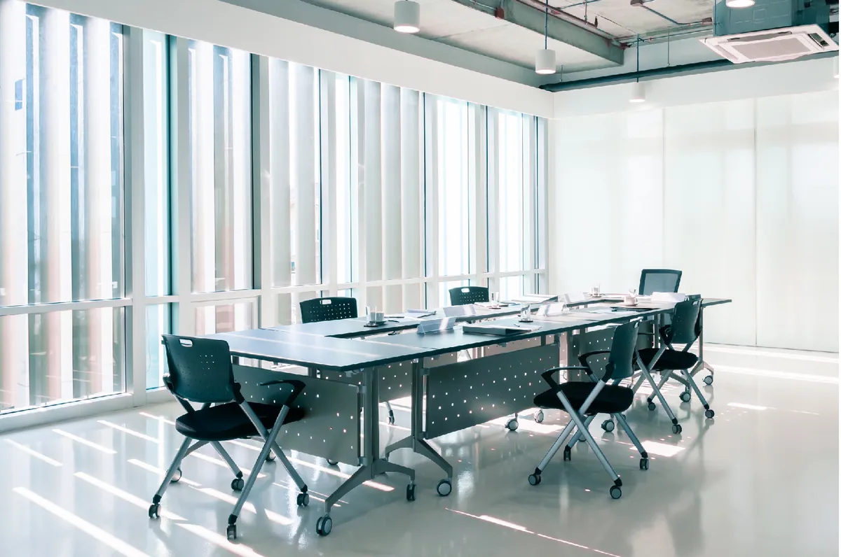 An empty corporate training room with long tables